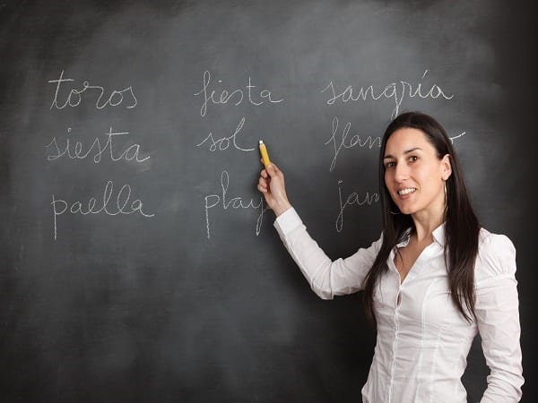 Woman showing spanish topics on a blackboard.